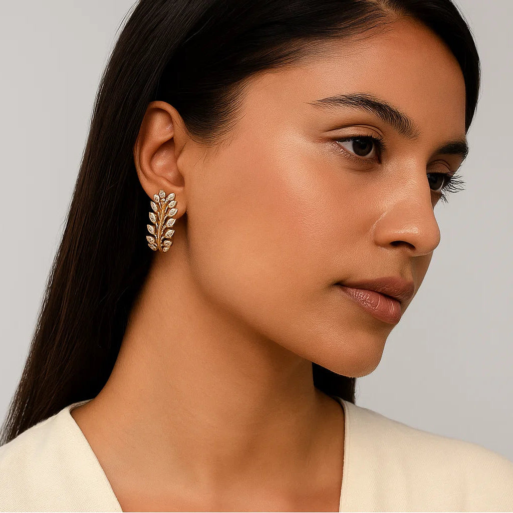 Woman wearing a leaf-shaped earring against a neutral background