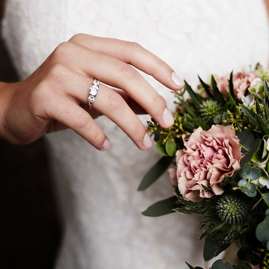 Hand with a ring touching a bouquet of flowers