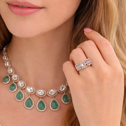 Close-up of a woman wearing a green teardrop necklace and diamond ring.