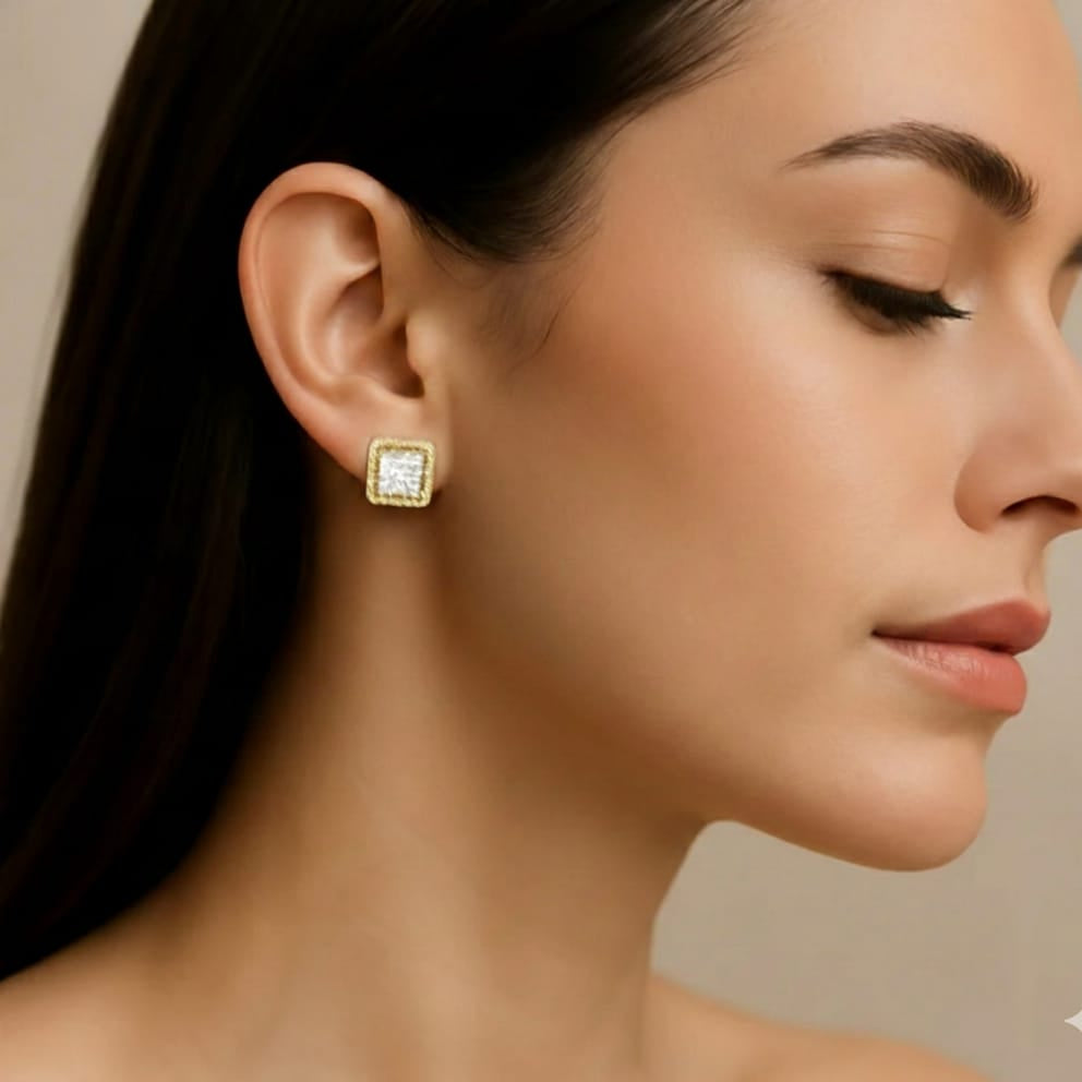 Close-up of a woman wearing gold square earrings with a neutral background