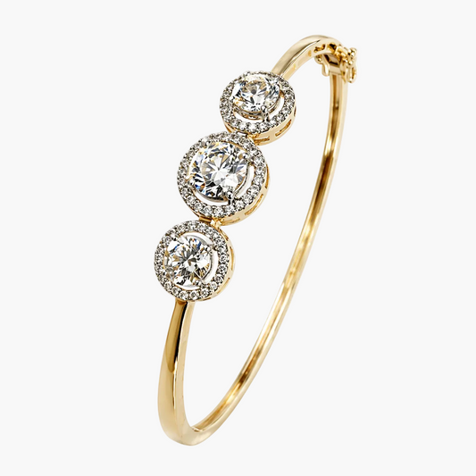 Gold bracelet with three circular diamond-like stones on a white background