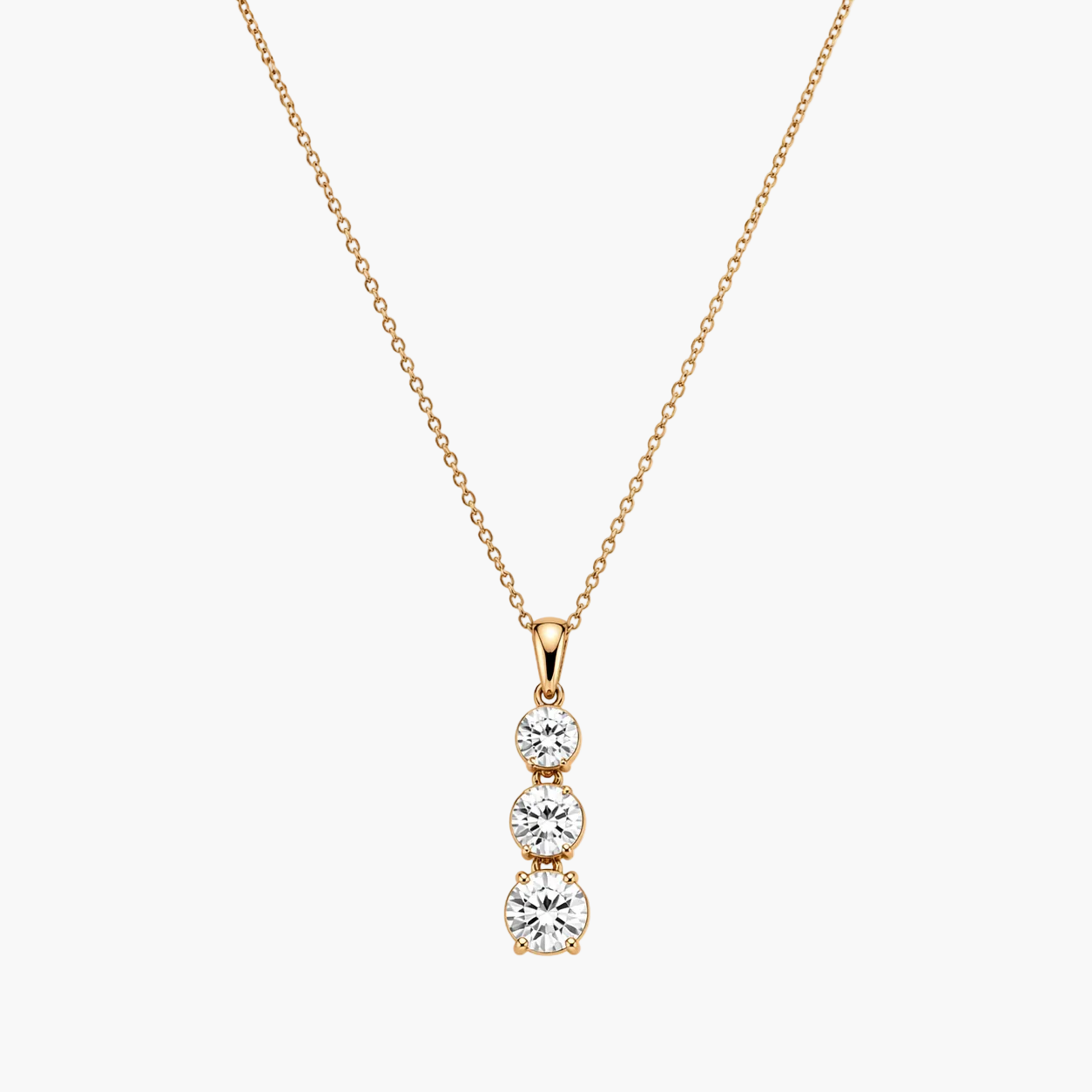 Gold necklace with a three-stone diamond pendant on a white background