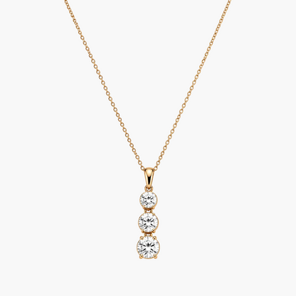 Gold necklace with a three-stone diamond pendant on a white background