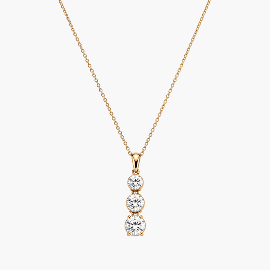 Gold necklace with a three-stone diamond pendant on a white background
