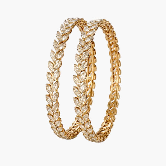 Gold hoop earrings with leaf-like design on a white background