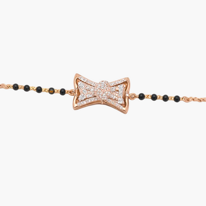 Rose gold bow-shaped bracelet with black beads on a white background