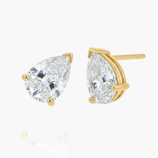 Gold earrings with pear-shaped clear gemstones on a white background