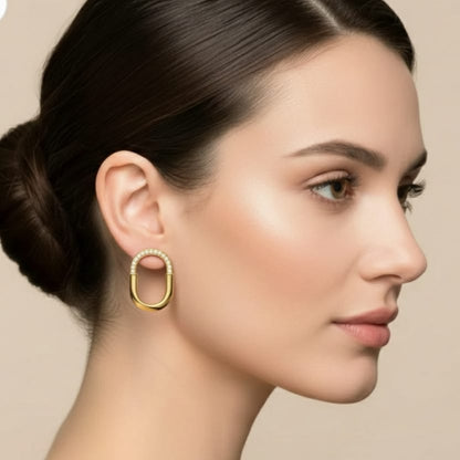 Woman wearing gold hoop earrings with a neutral background