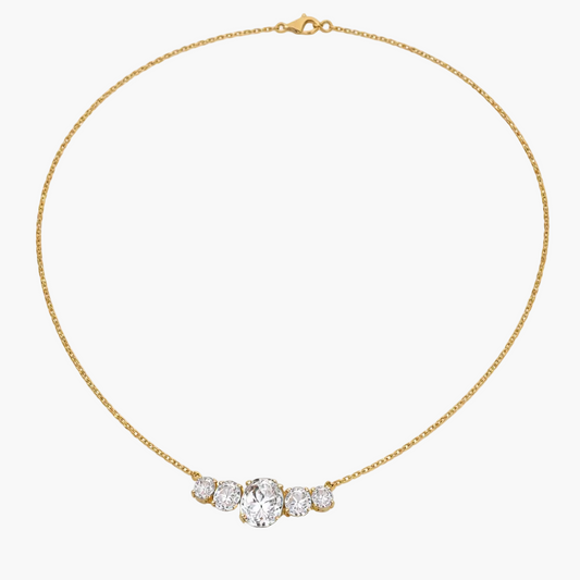 Gold necklace with a heart-shaped diamond pendant on a white background