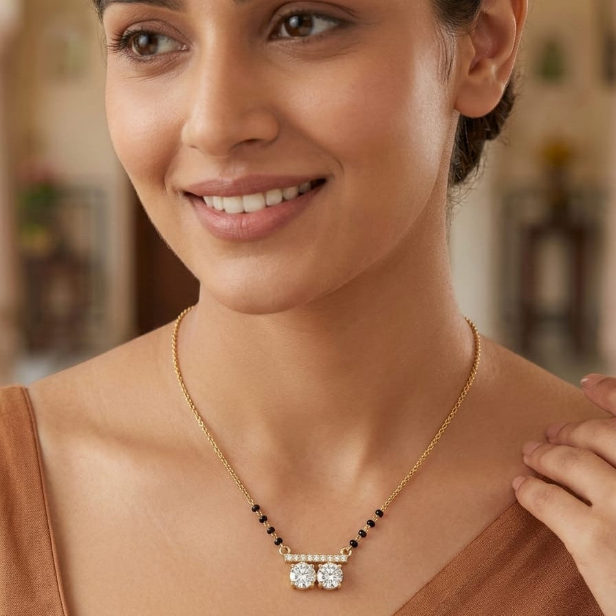 Woman wearing a gold necklace with a pendant in a blurred indoor setting