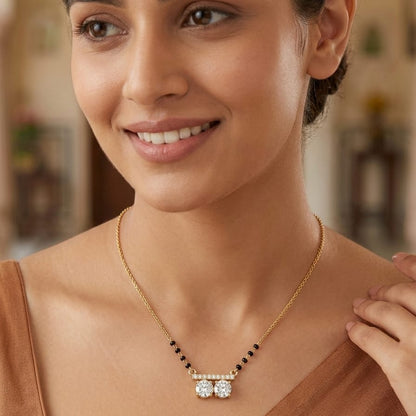 Woman wearing a gold necklace with a pendant in a blurred indoor setting