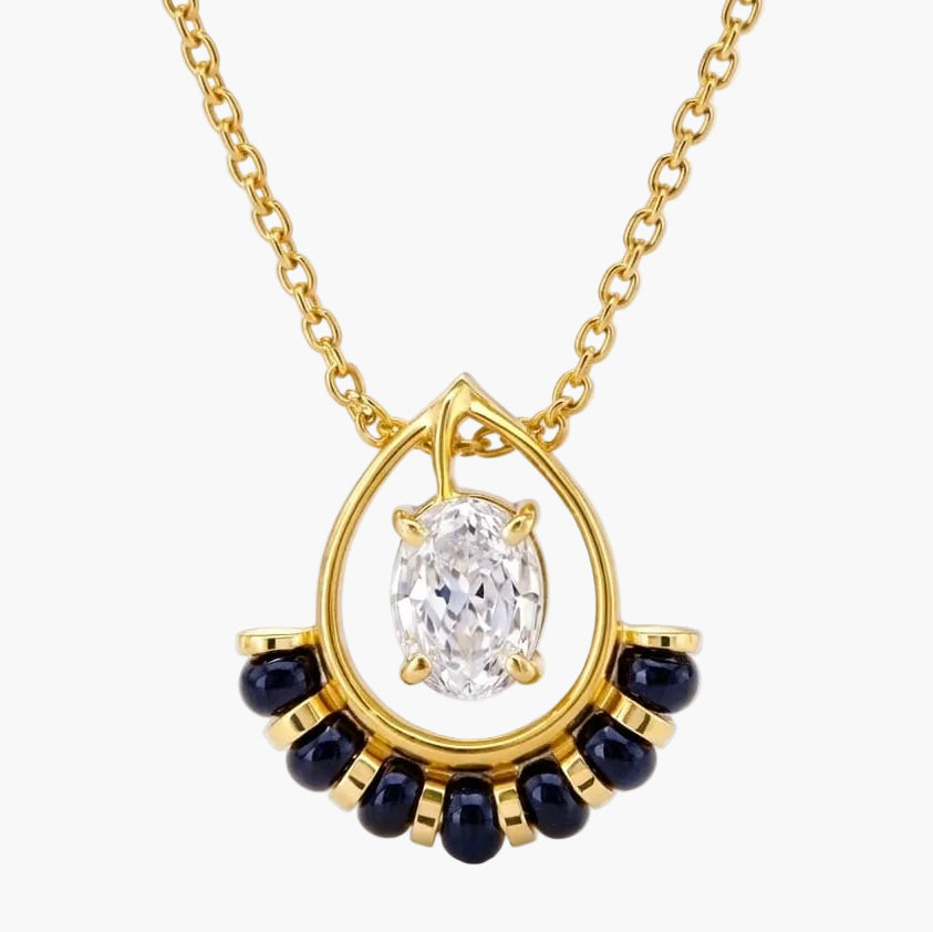Gold necklace with a diamond pendant and blue gemstones on a white background