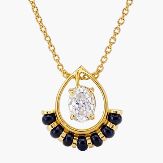 Gold necklace with a diamond pendant and blue gemstones on a white background