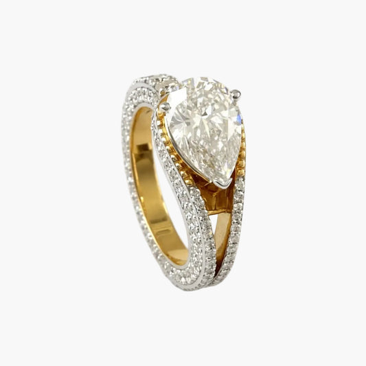 Gold ring with a pear-shaped diamond on a white background