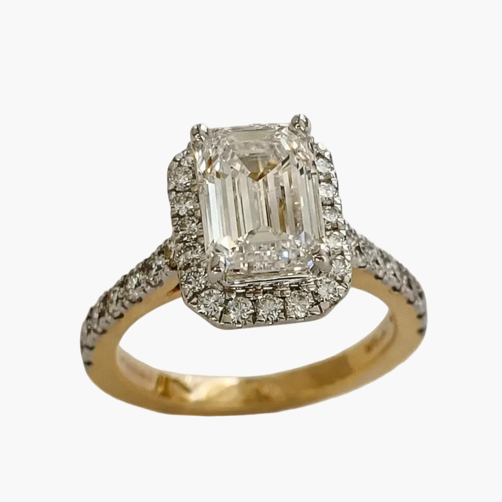 Diamond ring with emerald-cut center stone on a white background