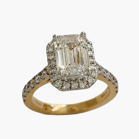 Diamond ring with emerald-cut center stone on a white background