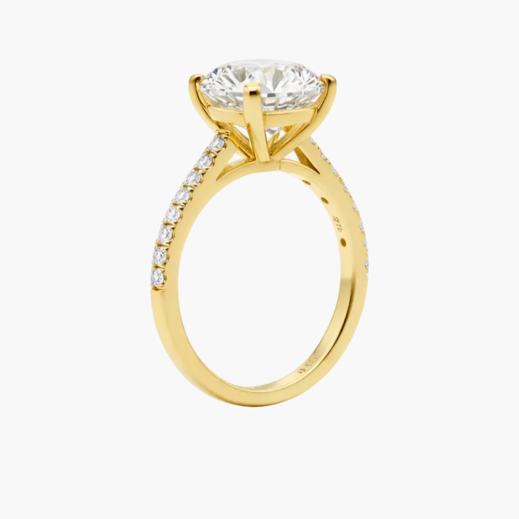 Gold ring with a large diamond and smaller diamonds on the band against a white background
