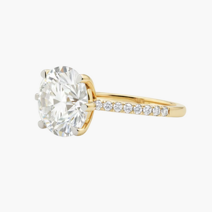 Gold ring with a large diamond and smaller diamonds on the band against a white background