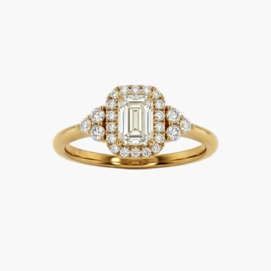 Gold ring with emerald-cut diamond and smaller diamonds on a white background