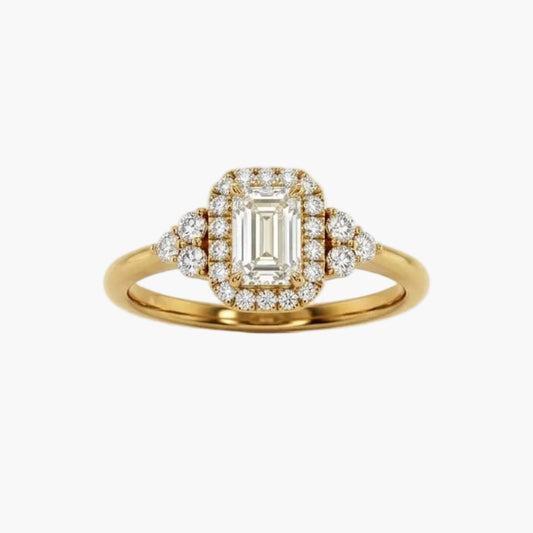 Gold ring with emerald-cut diamond and smaller diamonds on a white background
