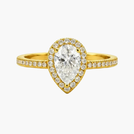 Gold ring with a pear-shaped diamond on a white background