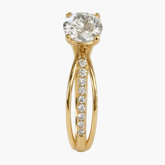 Gold ring with a large diamond and smaller diamonds on the band against a light gray background