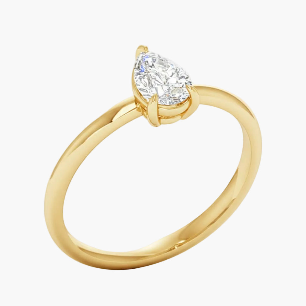 Gold ring with a pear-shaped diamond on a white background