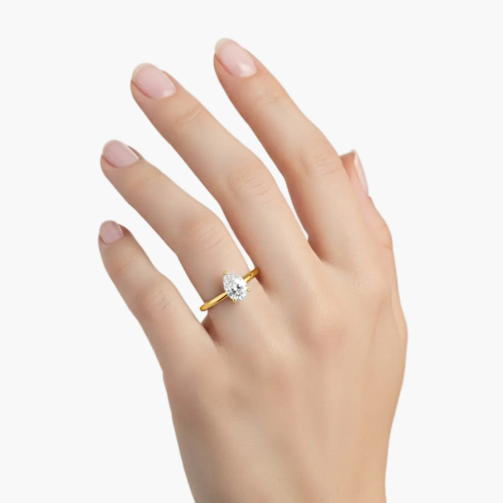 Gold ring with a diamond on a hand against a light background