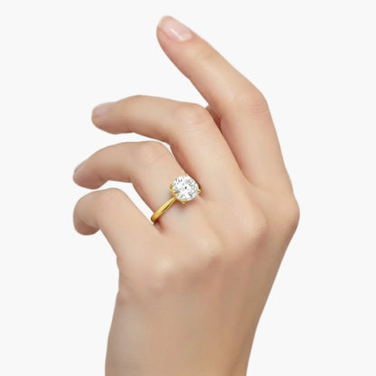 Gold ring with a diamond on a hand against a light gray background