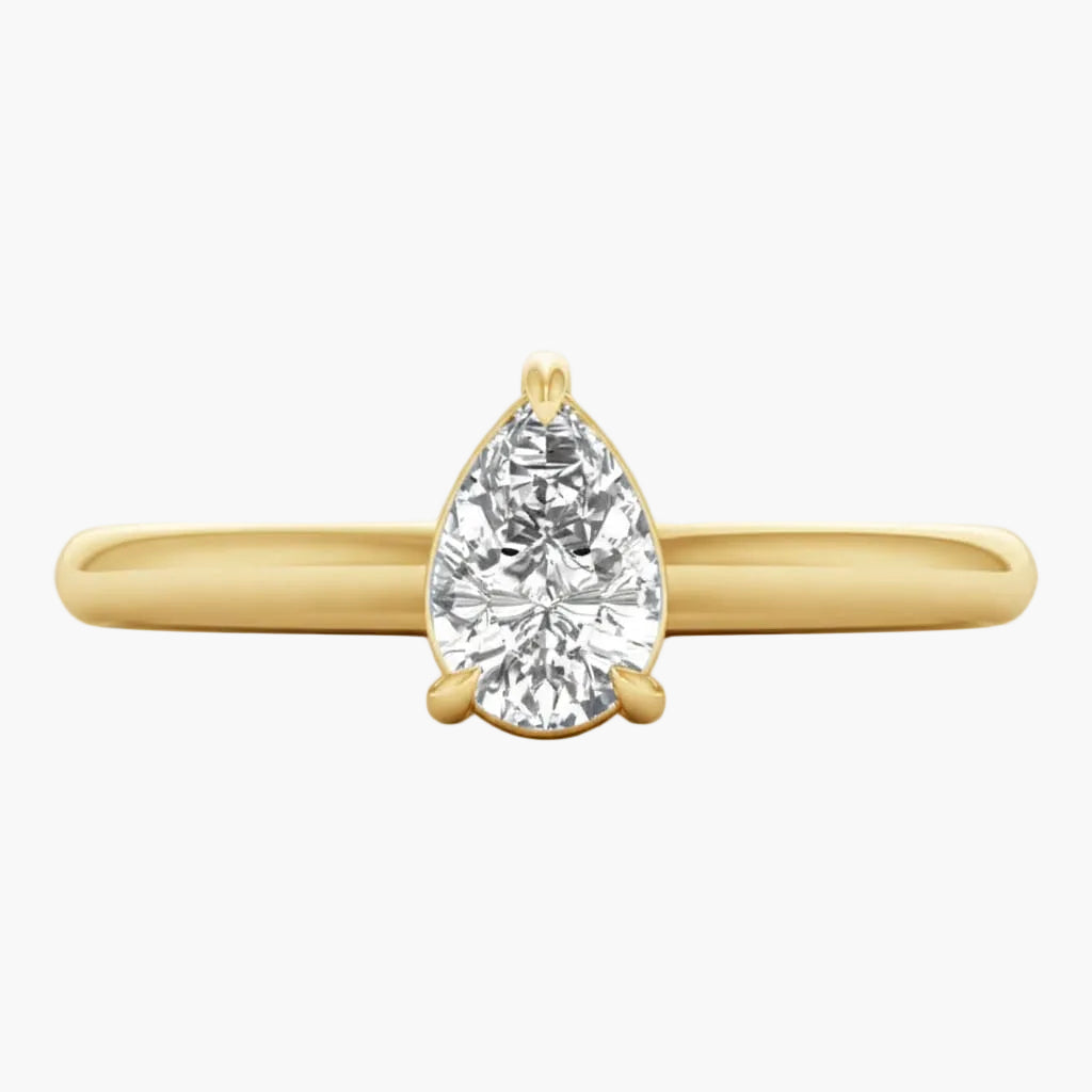 Gold ring with a pear-shaped diamond on a white background