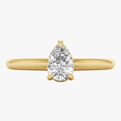 Gold ring with a pear-shaped diamond on a white background