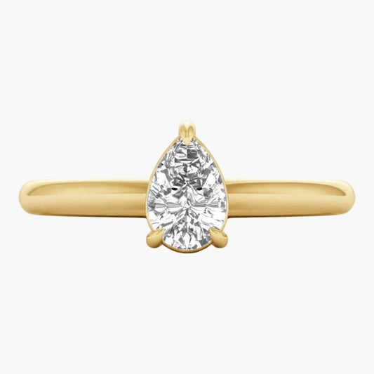 Gold ring with a pear-shaped diamond on a white background