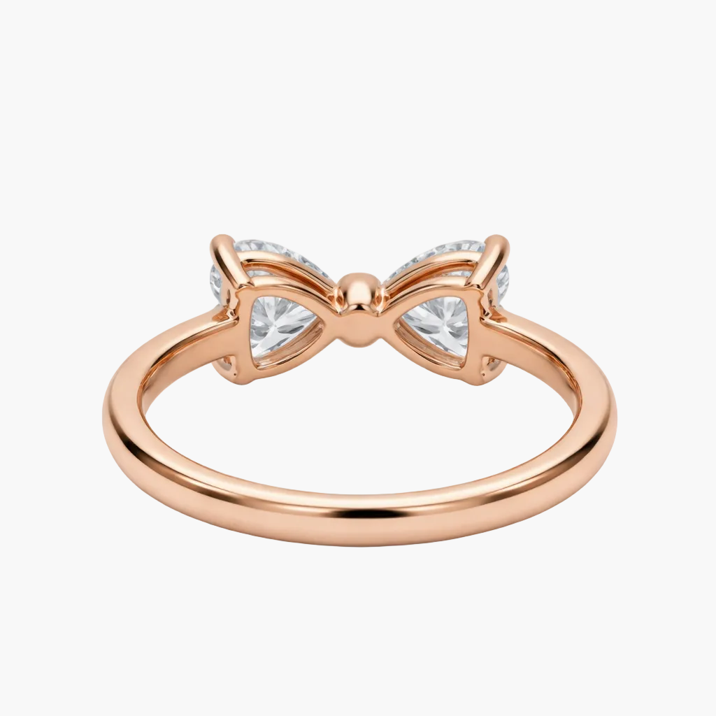 Rose gold bow-shaped ring with clear gemstones on a white background