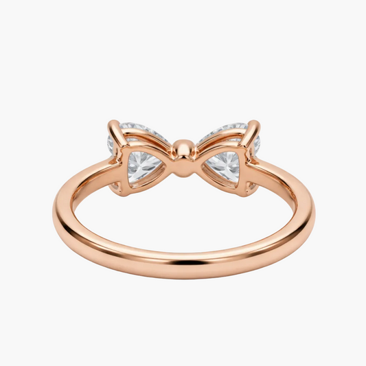 Rose gold bow-shaped ring with clear gemstones on a white background