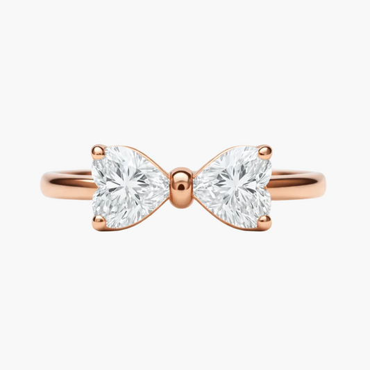 Rose gold bow-shaped ring with two heart-shaped diamonds on a white background