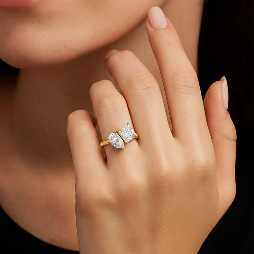 Gold ring with two diamonds on a hand against a black background