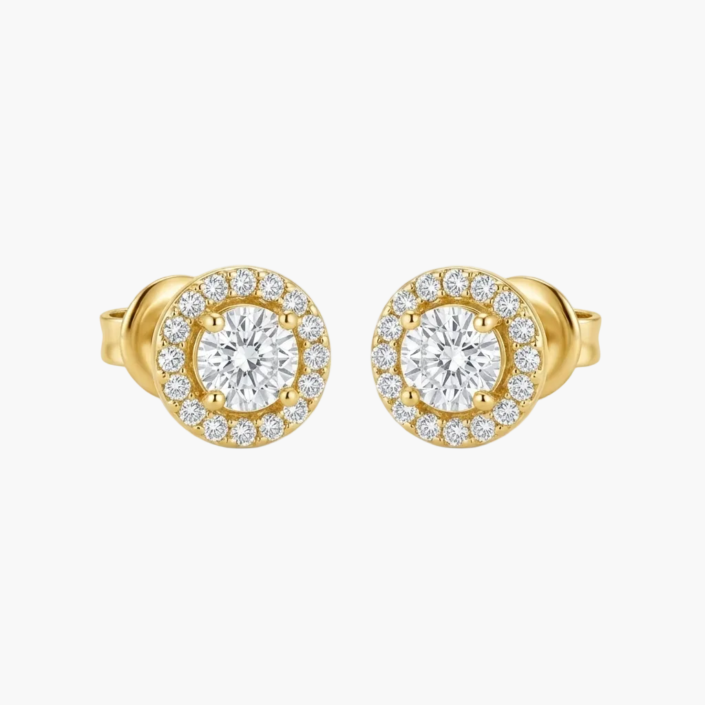 A pair of yellow gold stud earrings with a halo design, featuring a central round clear gemstone surrounded by a border of smaller clear stones, set against a plain light gray background.