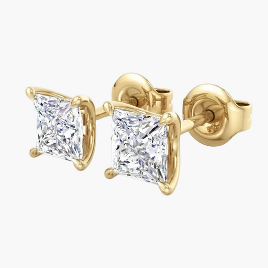 A pair of yellow gold stud earrings featuring princess-cut clear diamonds in four-prong settings, shown against a plain white background.