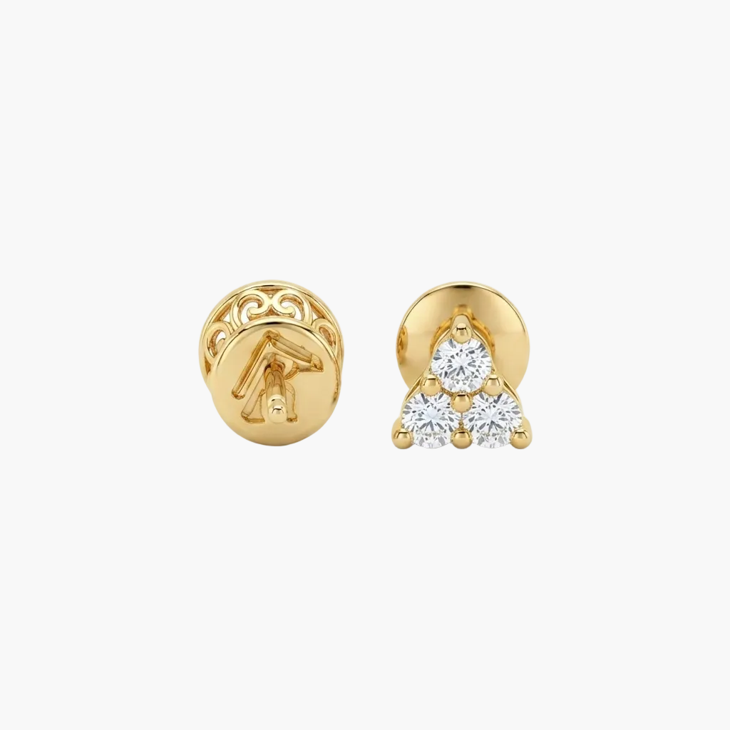 A pair of gold stud earrings on a light gray background. One earring is shown from the back, featuring an engraved symbol, while the other is shown from the front, featuring a triangular cluster of three clear gemstones in a gold setting.
