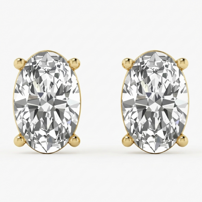 A pair of oval-cut diamond stud earrings in yellow gold four-prong settings, shown on a clean white background.