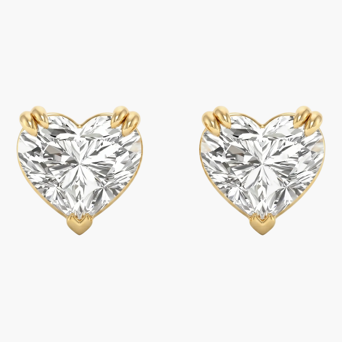 Heart-shaped diamond earrings with gold prongs on a white background