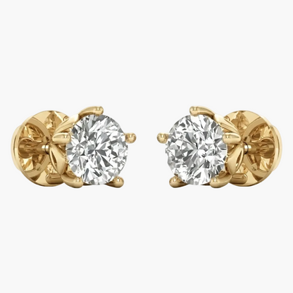 A pair of yellow gold stud earrings, each featuring a round brilliant-cut clear gemstone in a prong setting, shown against a plain light gray background.
