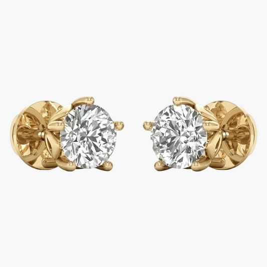A pair of yellow gold stud earrings, each featuring a round brilliant-cut clear gemstone in a prong setting, shown against a plain light gray background.