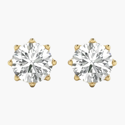 A pair of yellow gold stud earrings, each featuring a large round brilliant-cut diamond in a six-prong setting, shown against a plain white background.