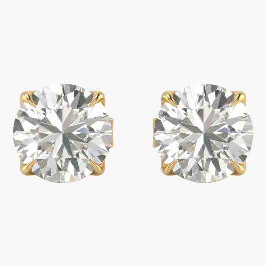 Pair of diamond stud earrings with gold prongs on a light gray background