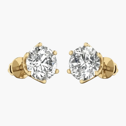 A pair of yellow gold stud earrings with large round brilliant-cut clear gemstones in a prong setting, shown on a plain white background.