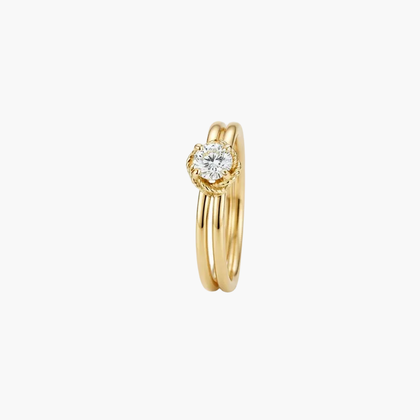 A gold double-band ring featuring a heart-shaped diamond halo, photographed on a clean white background.