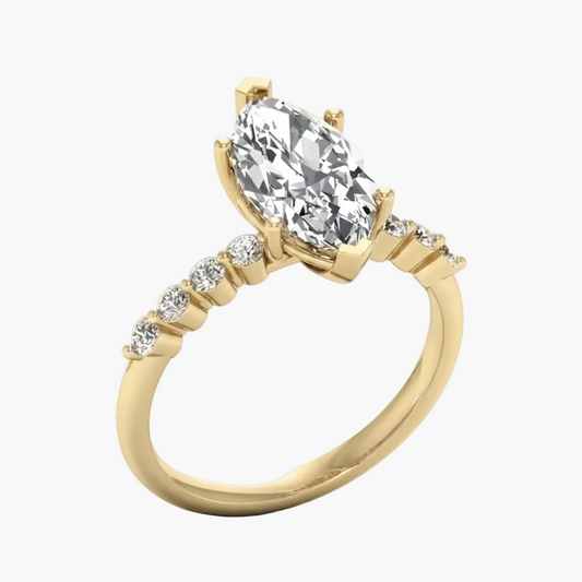 A yellow gold engagement ring featuring a large pear-cut center stone and a pavé band with smaller round stones, shown on a light gray background.