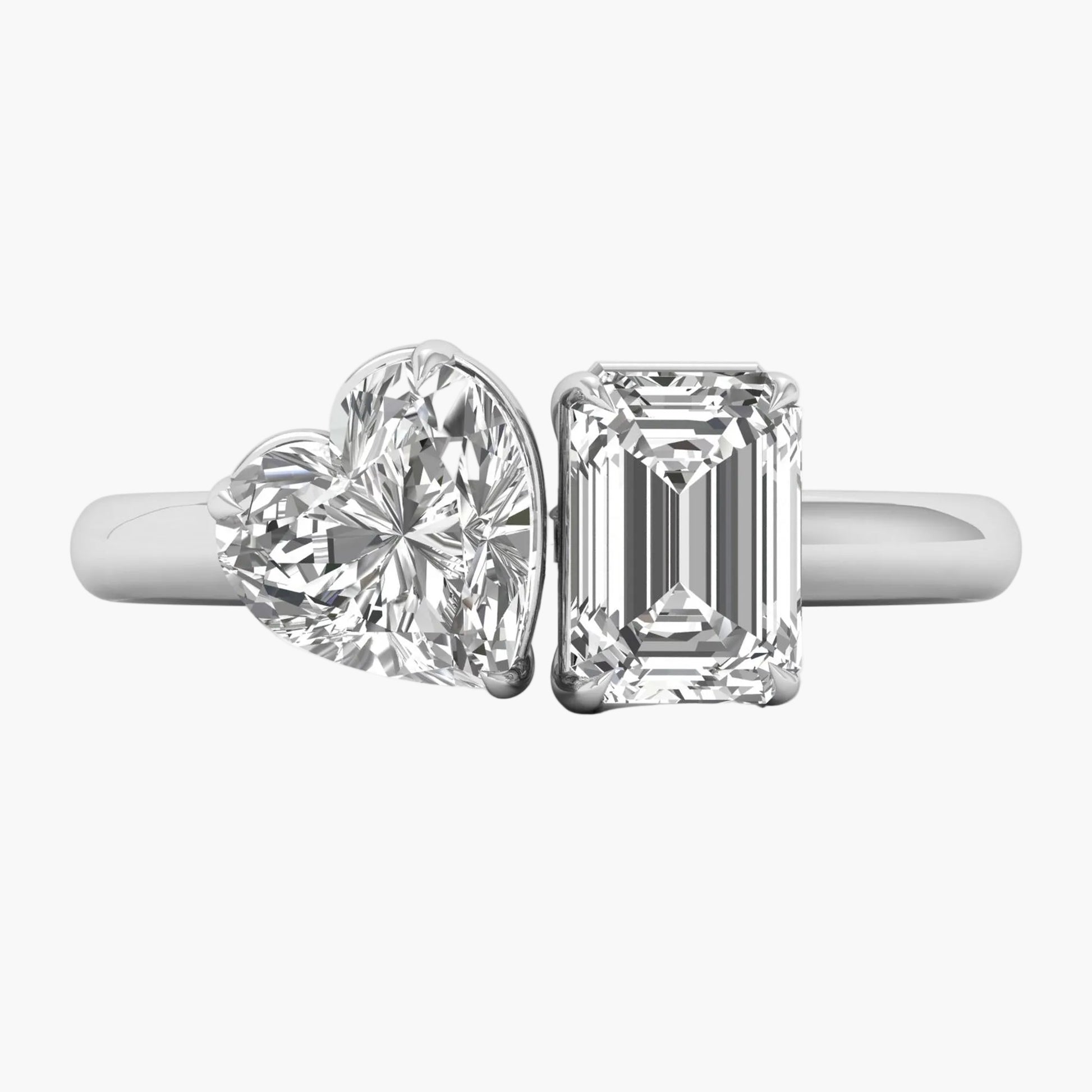 Two diamond rings, one heart-shaped and one emerald-cut, on a white background