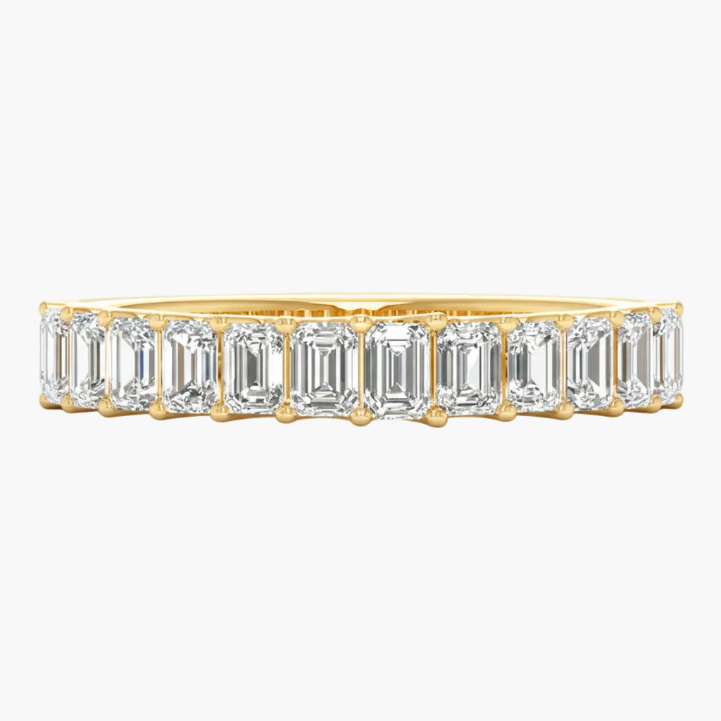 Gold ring with emerald-cut diamonds on a white background